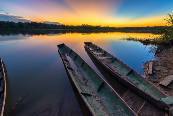Coucher de soleil dramatique dans la forêt amazonienne en Bolivie dans le parc national de Madidi avec deux canoës au premier plan